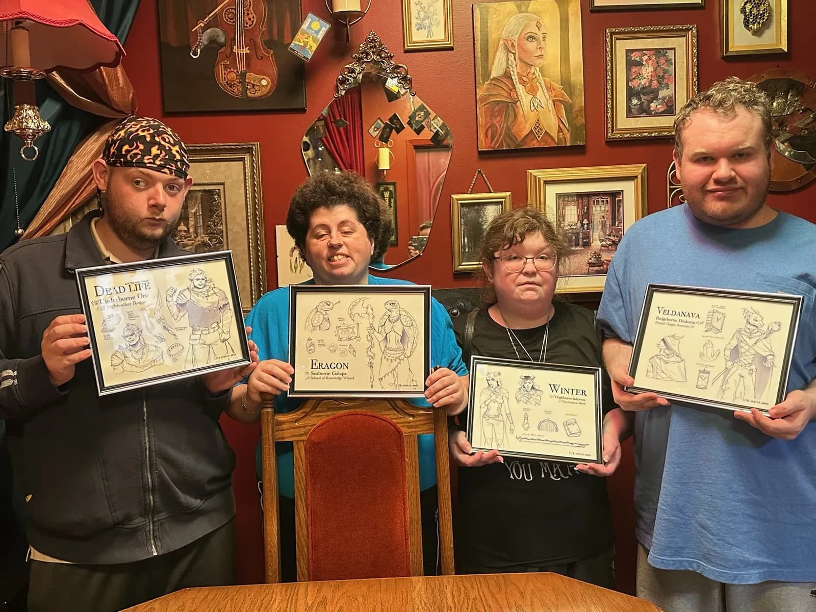 Four players holding their own finished, framed character commissions